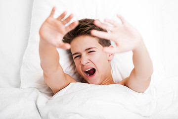 Happy handsome yawning child boy lying bed and resting