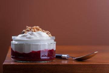 greek yogurt over raspberry jam and granola topping in a nice glass bowl