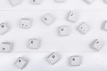 Keyboard keys isolated. White keyboard keys on white wooden background. Top view. Close up