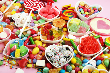 candies with jelly and sugar. colorful array of different childs sweets and treats on pink background