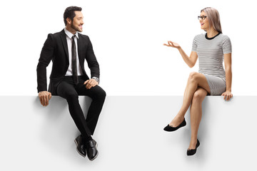 Young businessman and a young lady having a conversation while sitting on a panel