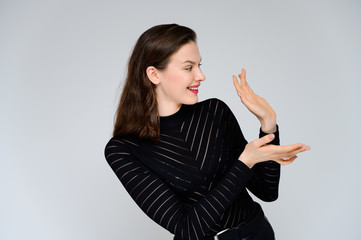 Concept adult girl on a white background. Large photo of a pretty brunette girl in a black sweater smiling and showing different emotions in different poses right in front of the camera.