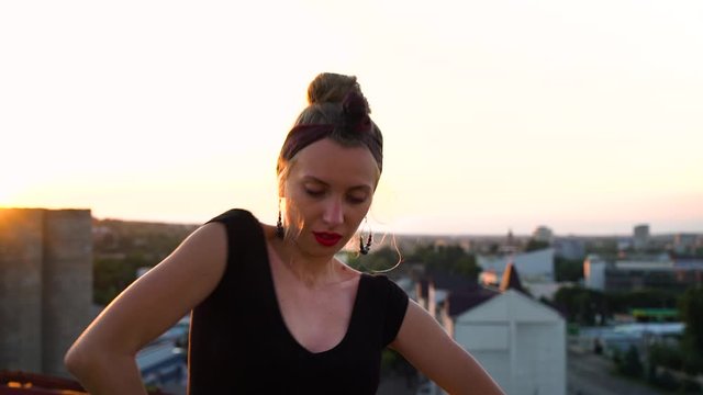 Young girl dancing waacking on industrial roof at sunset