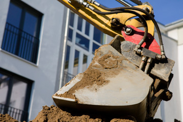 Excavator bucket digs sand on block background
