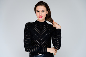 Concept adult girl on a white background. Large photo of a pretty brunette girl in a black sweater smiling and showing different emotions in different poses right in front of the camera.
