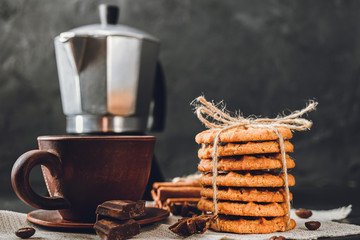 Homemade cookies and brown cup with coffee on dark background