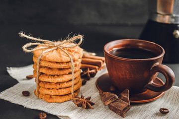 Homemade cookies and brown cup with coffee on dark background