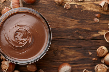 Chocolate spread with nuts on wooden background