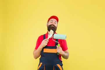 Man bearded laborer painting. Repair and renovation. Builder regular worker hold paint roller and brush. Perfect surface painting. Apply vinyl paint. Pick tools. Painting tool. Brush roller painter