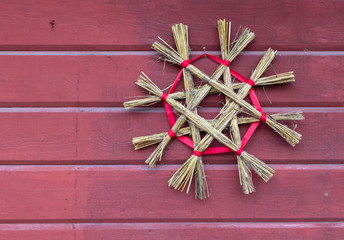 Traditional hay snowflake Christmas dekoration on a Scandinavian red plank wall