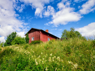 Lonely traditional red wooden cottage in summer at Lieto, Finland.