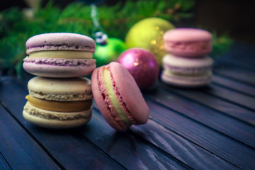 Tasty french macarons and christmas decorations on wooden background