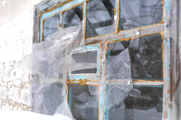 The old window is covered with cellophane film and covered with polyurethane foam. Poor building insulation in winter