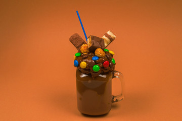 Chocolate milkshake with whipped cream, cookies, waffles, served in glass mason jar. 