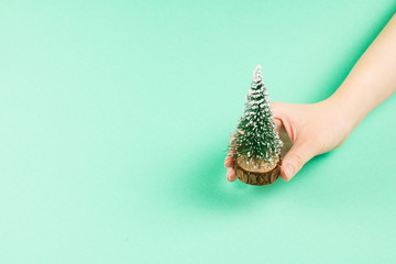 Small christmas tree in woman hand on a green background.