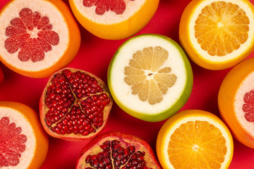 Grapefruit, orange, pomegranate, citrus sweetie on red background.