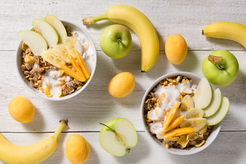 Plates with granola and fruits on a white wooden background. Healthy breakfast cereal