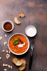 Two plates with a side dish of pumpkin with croutons, sour cream, pumpkin seeds, cilantro and spices on a white wooden background.