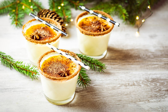 Eggnog with cinnamon and nutmeg for Christmas and winter holidays. Homemade eggnog in glasses on wooden table surface, shallow depth of the field, copy space.