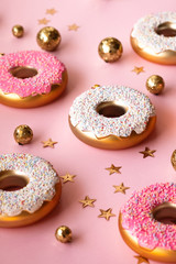 Christmas toys in the form of donuts on a pink background with gold decor, selective focus, side view. Creative food minimalism