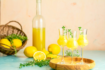 Limoncello with thyme in grappas wineglass with water drops on light concrete table. Artistic still...