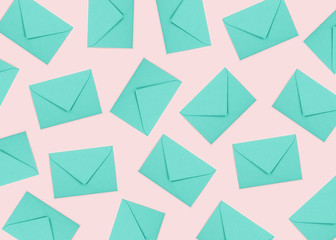 Pattern made of turquoise envelopes on pastel pink background.