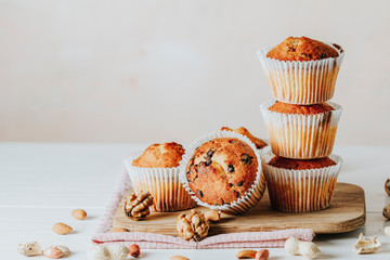 Vanilla caramel muffins in paper cups on white wooden background. Delicious cupcake with raisins,...