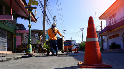 Naklejka premium Low angle view of electricians team with crane truck are working to install electrical cable lines on electric power poles with flare light and blue sky background at morning time