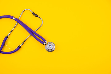 Medical stethoscope on trendy yellow background. Copy space.