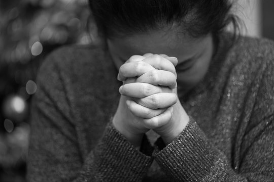 A black and white image of the concept. An Asian woman is clinging to God with what she wishes for healing. Sadness, pain, hope, and love in the bokeh background.