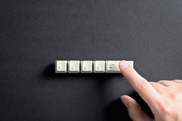 Computer keyboard keys with 2020 enter written using the white buttons on a dark background. Holiday technology concept. New year 2020 card.