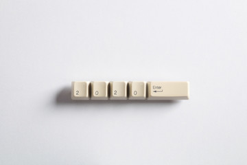Computer keyboard keys with 2020 enter written using the white buttons on a dark background. Holiday technology concept. New year 2020 card.