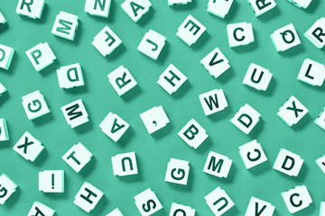letter cubes scattered on monochromatic green, dictionary or dyslexia reading difficulty and...
