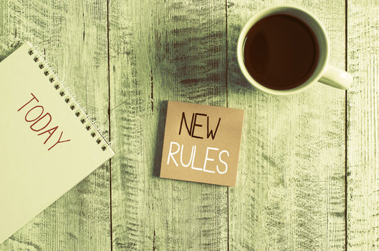 Conceptual hand writing showing New Rules. Concept meaning A state of changing an iplemented policy for better upgrade Stationary placed next to a coffee cup above wooden table