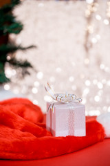 Christmas white gift box with a large bow standing on red hat santa calus against a background bokeh of twinkling golden bokeh lights. New Year's gift. Copy space