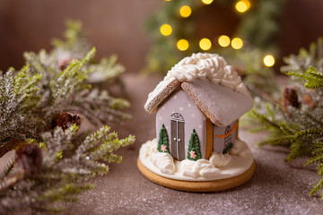 Gingerbread house on the background of a Christmas tree and a lie garland.