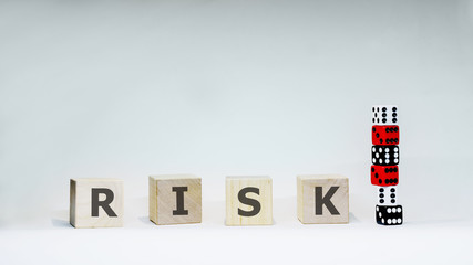 Word RISK with wooden letters with six dices on white background.