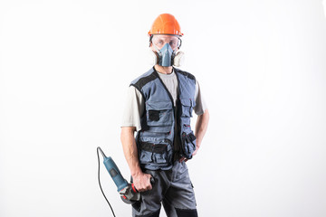 Naklejka premium Builder in a helmet and a respirator, with an angle grinder in his hands.