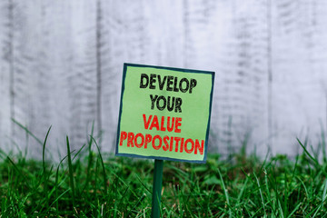 Conceptual hand writing showing Develop Your Value Proposition. Concept meaning Prepare marketing strategy sales pitch Plain paper attached to stick and placed in the grassy land