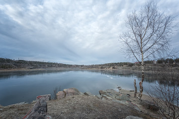 Frozen and ice-covered small lake with a rocky shore