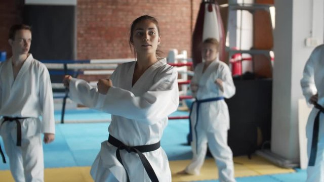 Panning of young female trainer teaching karatekas in sport center