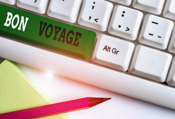 Conceptual hand writing showing Bon Voyage. Concept meaning used express good wishes to someone about set off on journey White pc keyboard with note paper above the white background