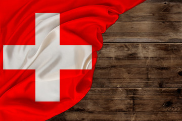 colored national flag of modern state of Switzerland, beautiful silk, old wood background, concept...