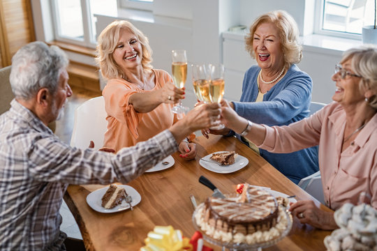 Cheerful Mature People Celebrating Birthday And Toasting With Champagne At Home.