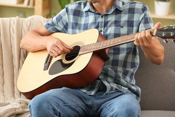 Handsome man playing guitar at home