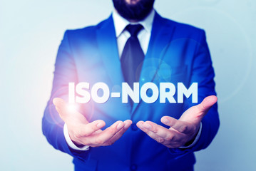 Text sign showing Iso Norm. Business photo showcasing An accepted standard or a way of doing things most showing agreed Man with opened hands in fron of the table. Mobile phone and notes on the table