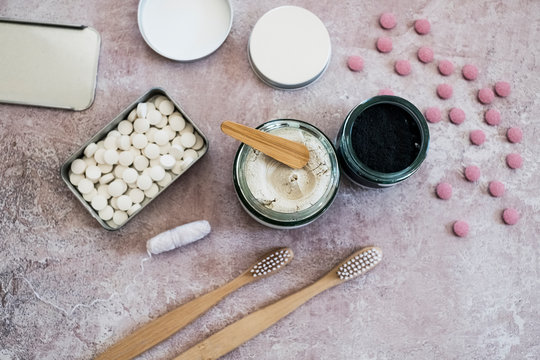 High angle close up of wooden toothbrushes, homemade cosmetics and pills in metal box.