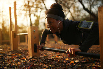 African American sportswoman practicing push-ups at at outdoor gym.