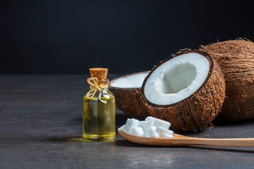 Glass bottle of coconut oil with fresh coconut fruit on rustic background, alternative theraphy...