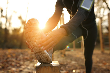 Close-up of African American athletic woman doing stretching exercises at sunset.